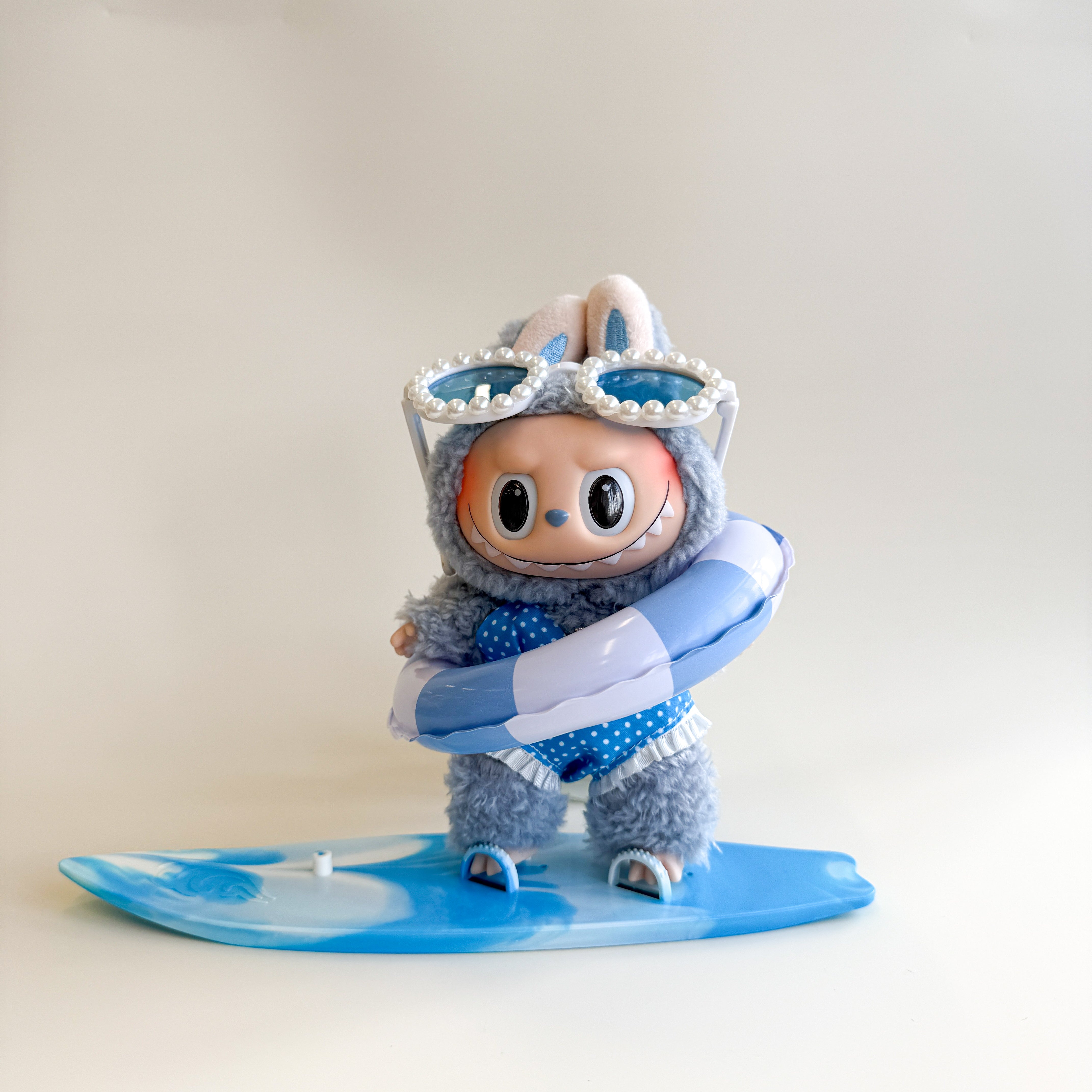 Flatlay of blue Labubu summer outfit with swim ring and skateboard