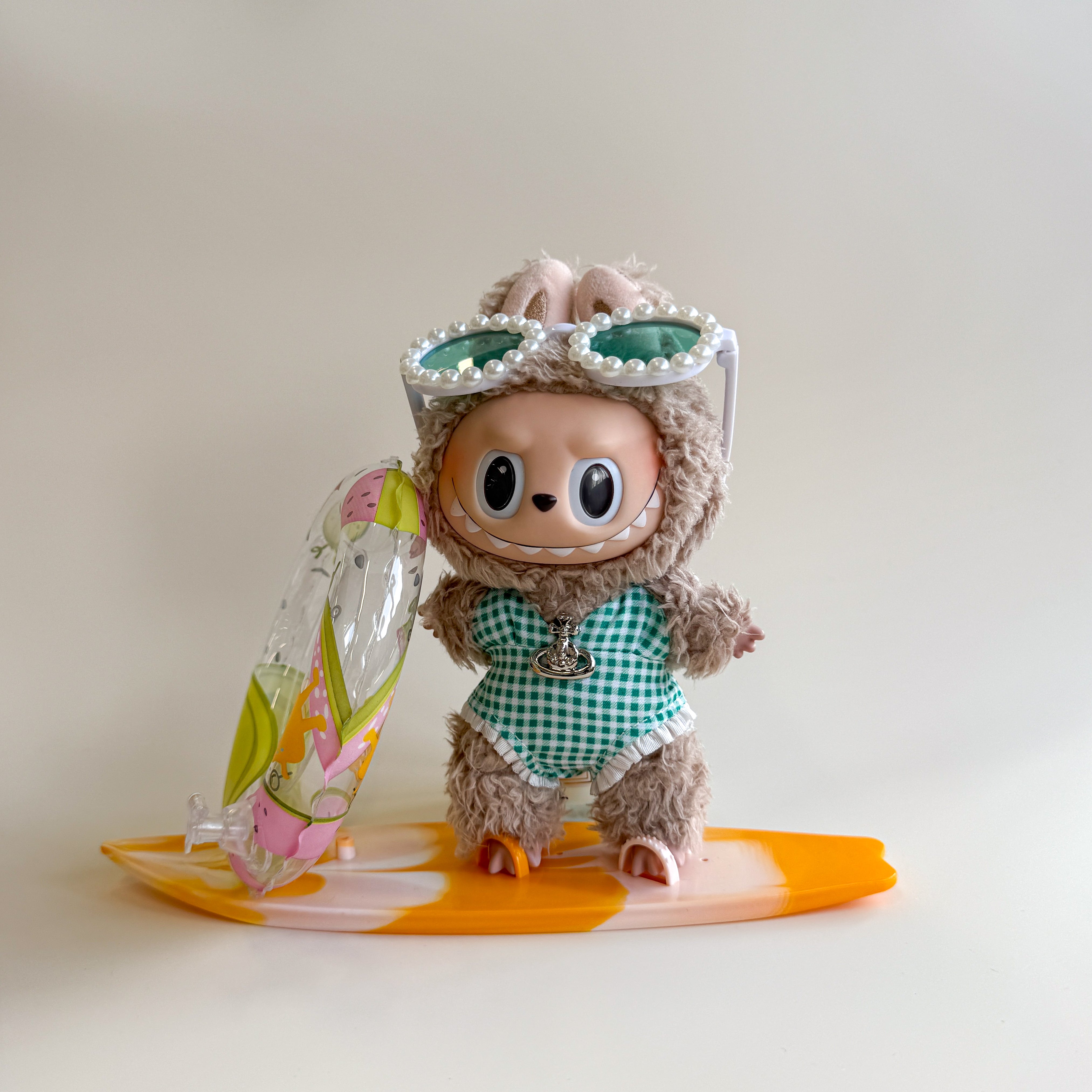 Flatlay of green Labubu summer outfit with swim ring and skateboard